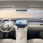 BYD interior mașini seal Europa | iDevice.ro Luxurious car interior with cream leather seats, a wide central touchscreen, and a digital instrument cluster amid a panoramic view outside the windshield