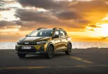 DACIA Sandero Stepway 2026 Hybrid Lansata ca o LOVITURA Directa in Masinile Chinezesti Golden SUV parked on a coastal road at sunset with the sea and orange sky in the background.