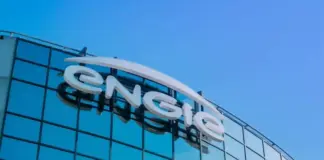 Partial view of a modern glass building with large white 3D letters mounted on a metal frame ( signage ) against a blue sky