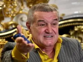 Man in a pinstripe suit and yellow shirt gesturing as he speaks in a lavish, gold-adorned room.