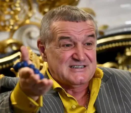 Man in a pinstripe suit and yellow shirt gesturing as he speaks in a lavish, gold-adorned room.