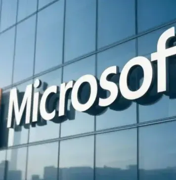 Microsoft logo displayed on a glass office building facade.