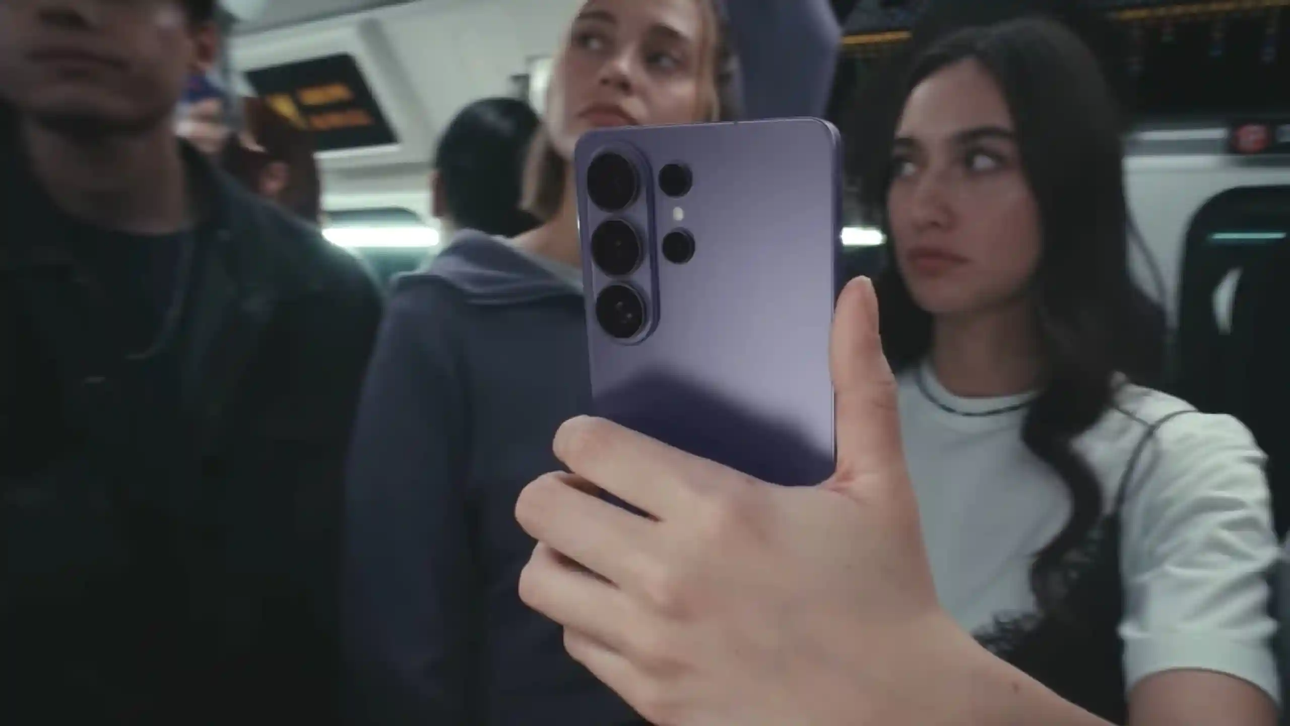 Person on a bus takes a selfie with a purple smartphone, other passengers blur in the background.