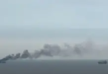 Atac in Marea Neagră, Nava LPG Gas Lisbon Lovită, Anunțul lui Nicușor Dan Large ship at sea emits a thick plume of dark smoke to the left, with another cargo vessel visible on the right over calm water.