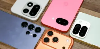 Several iPhone models with prominent camera bumps arranged on a wooden surface, showing white, pink, blue, orange, and green backs and multiple lenses per phone.