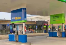 Fuel pumps under a white canopy at a MAXXMotion gas station with blue and green branding.