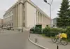 ANCPI a Hotarat ce va Bloca in eTerra Cand Redeschide Cadastrul, Motivul Limitarii Beige neoclassical building with tall columns beside a street; cyclist with yellow delivery bag rides past.
