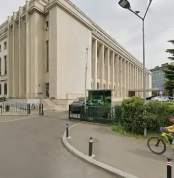 ANCPI a Hotarat ce va Bloca in eTerra Cand Redeschide Cadastrul, Motivul Limitarii Beige neoclassical building with tall columns beside a street; cyclist with yellow delivery bag rides past.