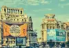 AVERTIZARI Cod ROSU si PORTOCALIU Meteo de ULTIM MOMENT Emise de ANM pentru Romania pe 3 August 2026 Historic city street with ornate old buildings, blue sky, and large orange banner in the foreground displaying Romanian text.