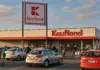 Catalog Kaufland cu Ofertele din Magazine pe 5 August 2026 pentru Card XTRA Kaufland supermarket exterior with a large red Kaufland sign and a parking lot in the foreground during daylight.