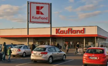 Catalog Kaufland cu Ofertele din Magazine pe 5 August 2026 pentru Card XTRA Kaufland supermarket exterior with a large red Kaufland sign and a parking lot in the foreground during daylight.