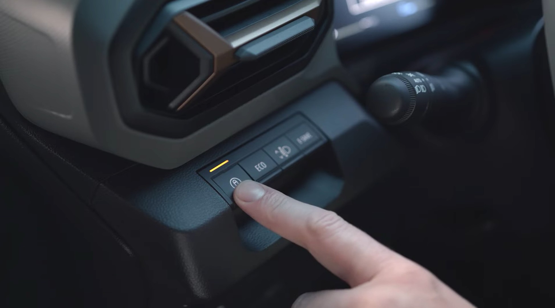 DACIA my Safety activare personalizare | iDevice.ro Close-up of a driver's finger pressing a button on the car's center console, amber indicator lit.