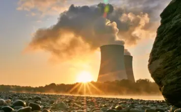 Dunarea Seaca pe Debit Scazut, Apele Romane Pregatesc Interventia pentru Protejarea Centralei de la Cenarvoda Industrial cooling towers releasing steam at sunset, seen from a rocky shoreline