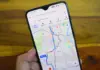Hand holds a smartphone showing a navigation app with colored routes and travel times on a city map