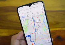 Hand holds a smartphone showing a navigation app with colored routes and travel times on a city map
