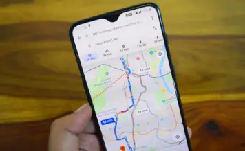Hand holds a smartphone showing a navigation app with colored routes and travel times on a city map