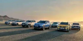 Row of modern SUVs lined up on a gravel surface at sunset, with mountains in the distance on the left.