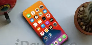 Close-up of a smartphone displaying a colorful home screen with many app icons on a light desk surface, angled from above.
