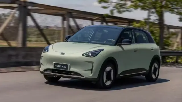 Geely E2. FOTO: Geely. Front-left three-quarter view of a pale green Geely EX2 electric SUV driving on a road.