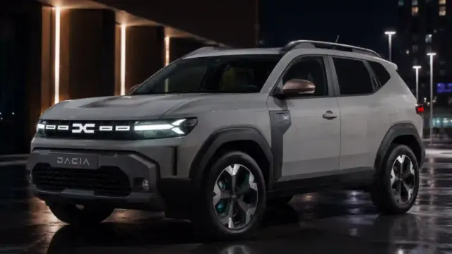 Front three-quarter view of a white SUV parked at night in a modern urban setting with reflective wet pavement and illuminated buildings nearby.